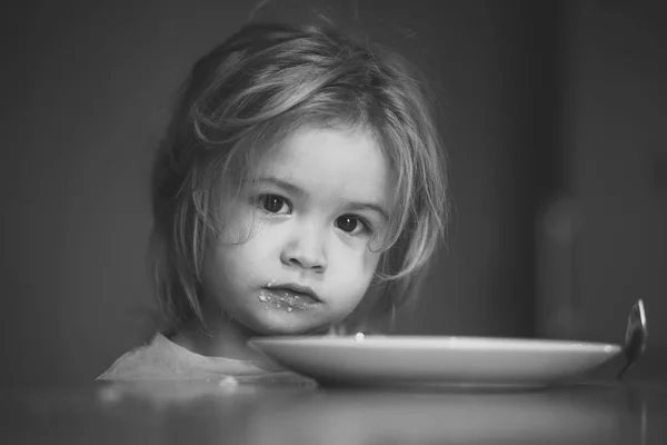 Child with empty plate, spoon after eating — Stock Photo, Image