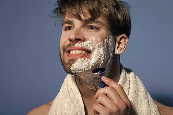 Ungkarl leende med raklödder, rakhyvel och handduk — Stockfoto