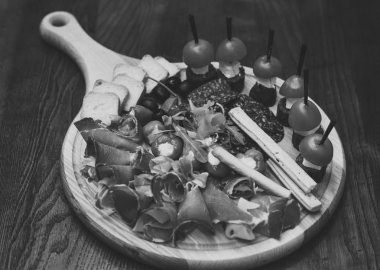 Ahşap masa snacks ile yönetim kurulu. Soğuk meze ile domates, sosis, salam, jambon, roka, zeytin ve ekmek. İştah açıcı atıştırmalıklar servis yönetim kurulu yuvarlak. Restoran yemek kavramı.