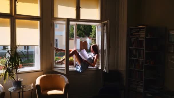 Молодая девушка сидит на окне и мечтает . — стоковое видео