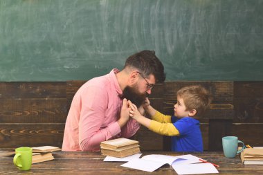 Erkek öğretmen açıklamalar küçük çocuğa vermek. Öğretmen ve onun küçük öğrenci davranış hakkında konuşmayı. Adam pembe gömlek ve sınıfta sarışın çocuk yan görünüm