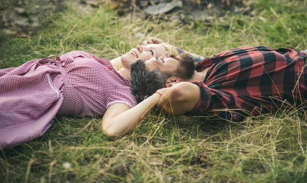 Side view couple lying on grass and looking at sky. Young people relaxing in park or forest. Summer holiday romance