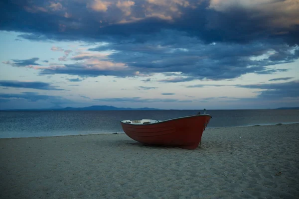 Bateau de pêcheurs au bord de la mer, sur le sable au coucher du soleil avec horisont mer sur fond. Concept de voyage et de repos. Fond de mer avec des vagues et ciel avec des nuages après la tempête. Bateau de pêche sur la plage le soir . — Photo