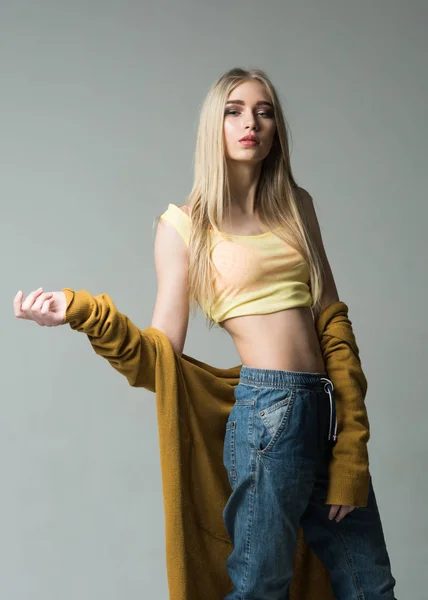 Menina loira com cabelo liso vestindo jeans estilo namorado e top amarelo isolado no fundo cinza — Fotografia de Stock