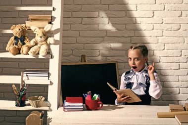 Kız renkli ileti örneğiyle masada oturuyor. Sınıfta çocuk