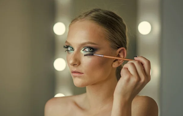 मेकअप मॉडल काजल applicator ब्रश का उपयोग करें। मेकअप महिला eyelashes पर मस्करा लागू करती है, देखो — स्टॉक फ़ोटो, इमेज
