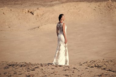 Çölde kum tepeleri üzerinde beyaz elbise duran kadın