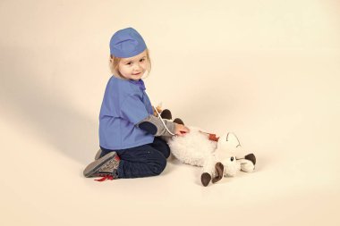 Doktor veteriner oyuncak hayvan ile oynarken üniforma içinde küçük çocuk