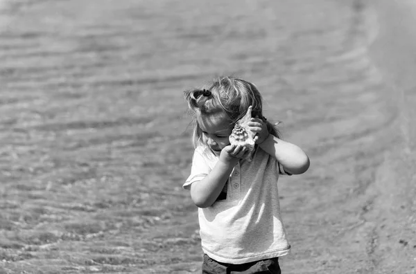 Söt baby pojke Lyssna på seashell på strand vid havet — Stockfoto