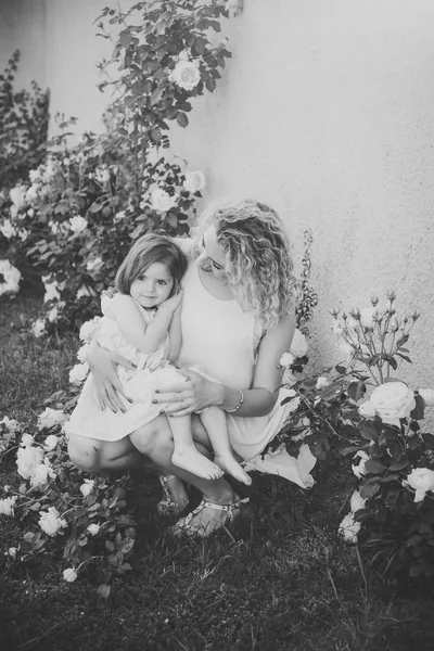 Mom cuddling daughter on green grass — Stock Photo, Image