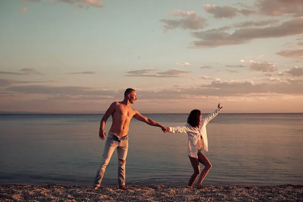 Mann und Frau halten Händchen, Paar glücklich im Urlaub. verliebte Paare tanzen, Spaß haben, Meer und Skyline Hintergrund. Verliebte Paare stehen am Strand, am Strand. Flitterwochen, frisch verheiratet — Stockfoto