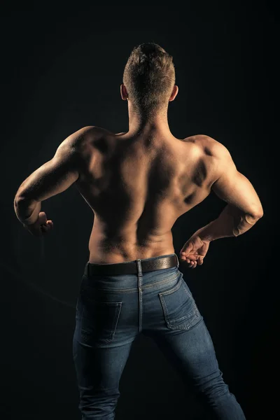 Sportsman mostra muscoli su sfondo scuro — Foto Stock