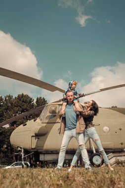 Mutlu aile zaman harcamak birlikte, gezi, arka plan, helikopter üzerinde güneşli bir gün. Aile Eğlence kavramı. Anne ve baba ve Havacılık Müzesi havada yürüyen çocuk.