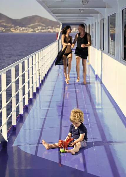 Famiglia che viaggia su una nave da crociera, sfocata. Il concetto di riposo familiare. Padre, madre cammina sul ponte della nave da crociera mentre il bambino gioca con il giocattolo, paesaggio sullo sfondo . — Foto Stock