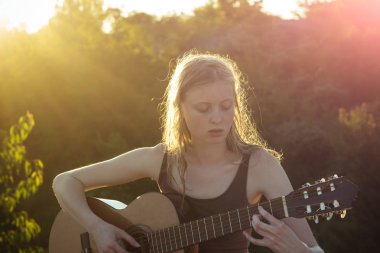 Alanında oturup ve gitar çalmak genç kadın