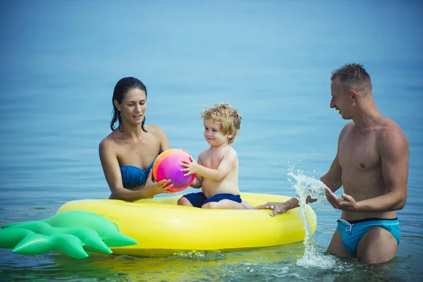 Glückliche Familie hat Spaß mit Luftmatratze am Strand. — Stockfoto