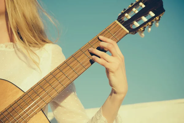 Müzik ve eğlence kavramı. Gitar dizeleri tıngırdatmaya parmak ile. El yaylı çalgılar üzerinde oynamak. Klasik gitar boyun fretboard ve güneşli mavi gökyüzü üzerinde sap kafası