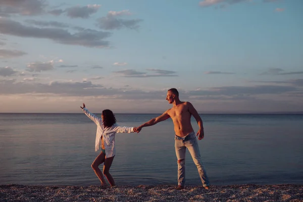 Homme et femme se tiennent la main, couple heureux en vacances. Couple en amour dansant, s'amusant, fond de mer et d'horizon. Couple amoureux debout sur la plage, bord de mer. Lune de miel, concept de mariage . — Photo