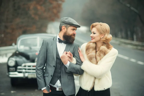 Casal perto de um carro retro ao ar livre andando . — Fotografia de Stock