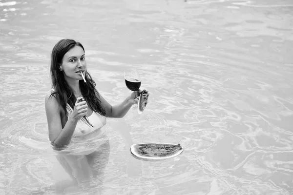 Девушка курит с арбузом и вином в бассейне — стоковое фото