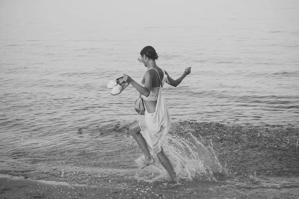 Fiatal gyönyörű hölgy fut a víz csobbanás, tenger, vagy óceán beach. Szabadság fogalmát. Nő hordozza a cipő a kezében, és séta a tenger hullámai. Szabad és független nő a nyaralás — Stock Fotó