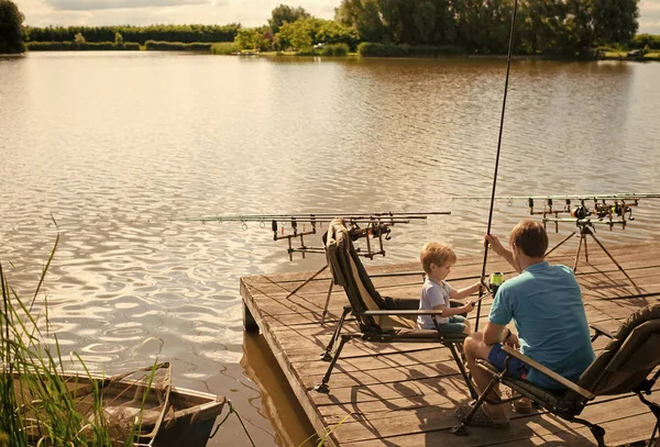 Отец учит сына ловить рыбу на берегу озера — стоковое фото