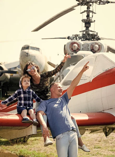 Matka, ojciec i dziecko podekscytowany siedzieć na samoloty skrzydło w muzeum lotnictwa. Szczęśliwa rodzina patrząc na niebo, na wycieczkę, helikopter lub samolot na tle, słoneczny dzień. Koncepcja rozwoju i wychowania — Zdjęcie stockowe