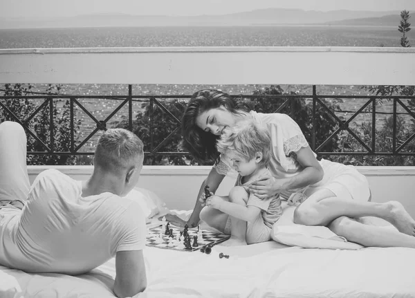 작은 아들과 함께 가족 발코니, 자연과 배경에 바다에 체스를 재생 합니다. 아빠와 엄마가 자녀와 함께 게임을 지적 한다. 스마트 아이 개념. 부모 체스 아이 함께 테라스에서 화창한 날에. — 스톡 사진