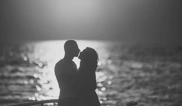 Silhueta de casal sensual beijando com o pôr do sol acima da superfície do mar no fundo. Casal apaixonado na data romântica à noite em frente ao mar, desfocado, espaço de cópia. Romance e amor conceito . — Fotografia de Stock