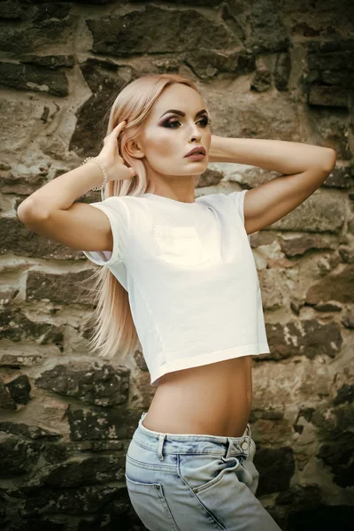 Όμορφη νεαρή σέξι μόδας θέτοντας σε φόντο τοίχο αισθησιακή γυναίκα, ντυμένη με στολή στυλ τζιν — Φωτογραφία Αρχείου
