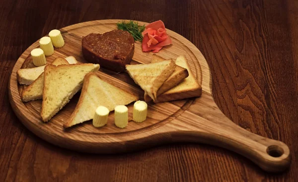 Befsztyk tatarski serwowane w kształcie serca na cały pokład drewniany. Chleb, tosty i masła, wokół befsztyk na pokładzie. Koncepcję danie w restauracji. Danie apetycznie urządzone z koperkiem — Zdjęcie stockowe