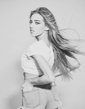 Saç bakım kavramı. Sağlıklı parlak saçlar ile seksi bir bayan. Uzun saçlı kız kısa kot şort, açık renkli giyer. Kadın sakin yüz havada sallayarak saçını zevk çekici