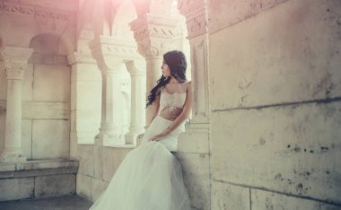 Moda modeli ya da prenses. Yaz aylarında taş eski kule kadında. Şatodaki düğün töreninde gelin kız. Düğün moda ve güzellik salonu. Şık saç ile beyaz elbiseli seksi kız