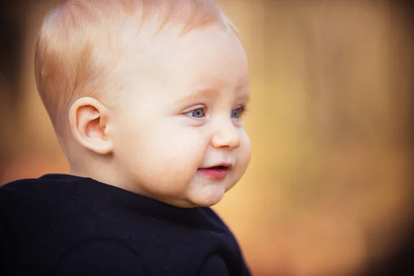 Niño con una sonrisa adorable al aire libre. Niño sonriendo en la naturaleza borrosa, espacio de copia — Foto de Stock