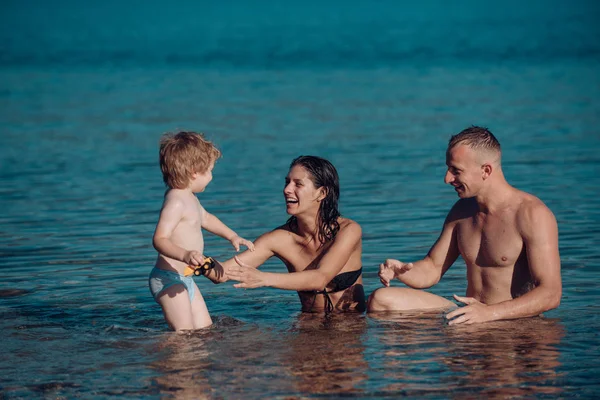 父と息子と母はビーチに海で泳ぐ。父と海や海の水で幸せな子供を持つ母. — ストック写真