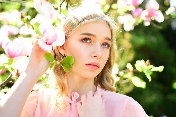 Mädchen mit verträumtem Gesicht, zarte Blondine in der Nähe von Magnolienblüten, Naturhintergrund. Frühjahrsblüher Konzept. junge Frau liebt Blumen im Garten. Dame spaziert an sonnigem Frühlingstag im Park. — Stockfoto