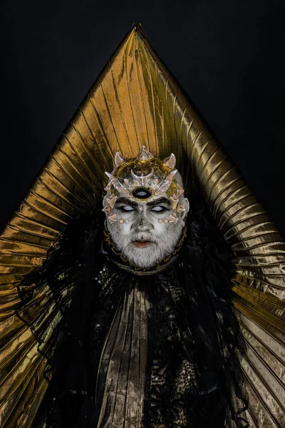 Hombre con tercer ojo, espinas o verrugas. Demonio con cuello dorado sobre fondo negro. Hombre mayor con barba blanca vestido de monstruo. Alien, demonio, maquillaje de hechicero. Concepto de horror y fantasía . — Foto de Stock