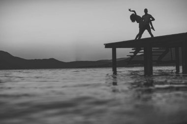 Şehvetli çift deniz yüzeyi arka plan üzerinde yukarıda gün batımı ile rıhtımda dans silüeti. Romantizm ve aşk kavramı. Dock, kopya alanı, akşam romantik tarihte aşık Çift