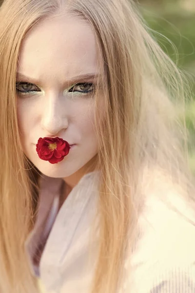 Dámské den, 8 březen, jaro koncept. Žena s červenou květinou v ústech, 8 březen. Modelka má dlouhé blond vlasy, účes na přírodu. Krásy dívka s glamour vzhled, make-up — Stock fotografie