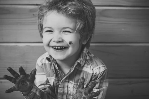 Хлопчик художник щасливий посміхається на дерев'яній стіні — стокове фото