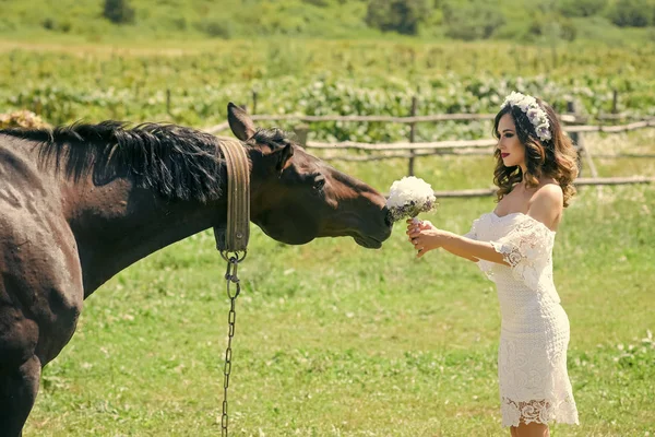 Mulher noiva dar buquê de flores para cavalo — Fotografia de Stock