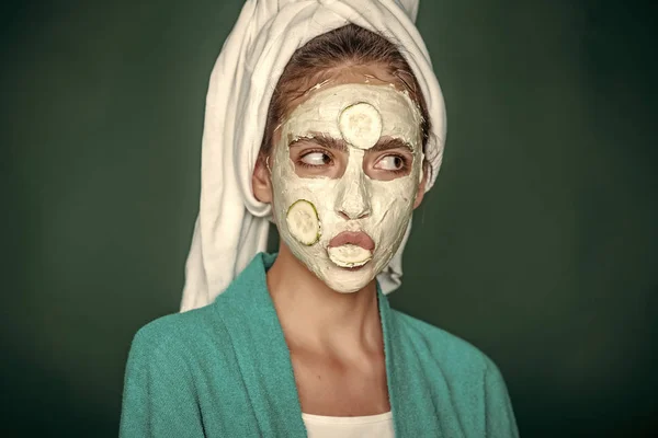 Menina com pepino na boca, máscara facial no fundo verde — Fotografia de Stock