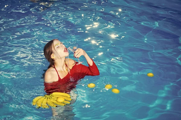 Mujer relajarse en la piscina de spa. mujer con frutas tropicales en la piscina. La vitamina en el plátano a la muchacha que se sienta cerca del agua. Dieta y comida orgánica saludable, vegetariana. Vacaciones de verano y viajes al océano — Foto de Stock