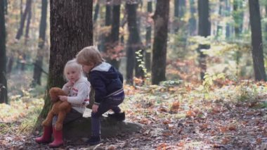 Mutlu küçük çocuk, küçük kız gülerek ve oynayarak sonbaharda doğa yürüyüşünde.
