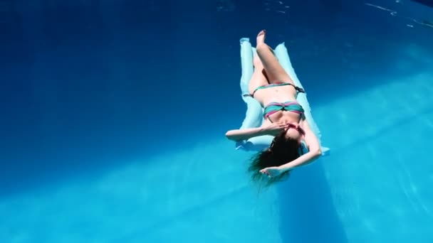 Chica milenaria flotar en la piscina, festival, hotel, playa, evento sonriendo con gafas de sol en verano. Disfrutando del bronceado. Concepto de vacaciones. Vista superior de la mujer joven delgada en bikini en el aire azul — Vídeos de Stock