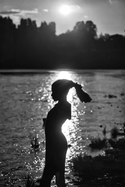 Silhouette féminine près de l'eau au coucher du soleil — Photo