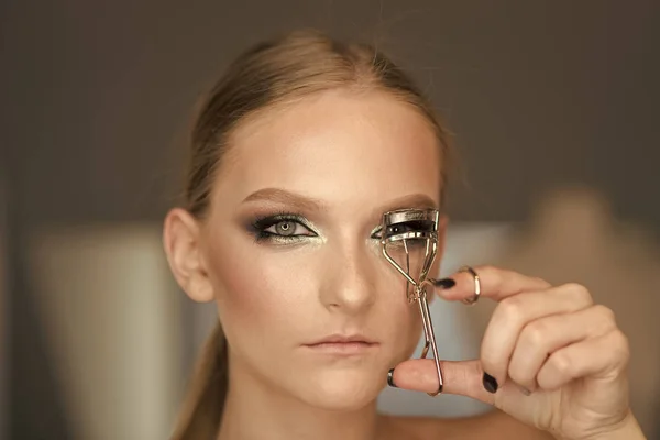 Woman use eyelash curler for eye makeup. Woman curl lashes with beauty tool, look. Model with curly long eyelashes, beauty. Fashion makeup for glamour girl, visage course