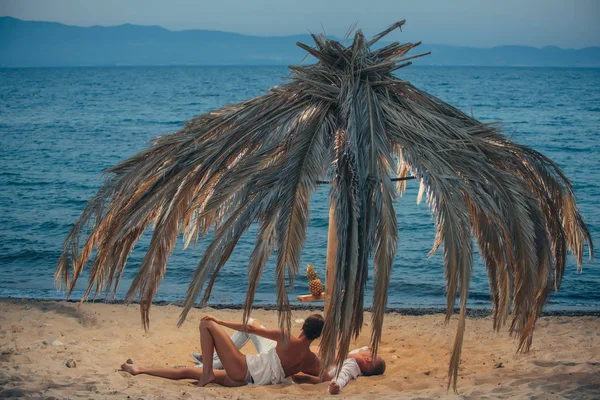 Jeune homme et femme se détendre sur le sable chaud près d'une mer et regardant quelque part . — Photo