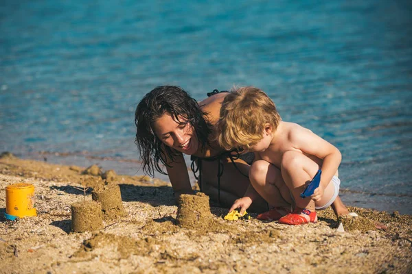 Moeder met zoon make zand kasteel op zee. Gelukkige familie op de Caribische zee. Zomervakantie en reizen naar de Oceaan. Maldiven of Miami beach activiteit vreugde. Moeders daagse vakantie van kleine jongen en vrouw ouder. — Stockfoto