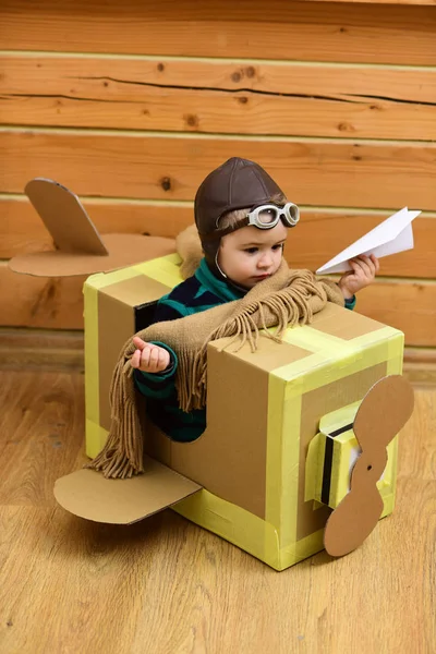 Kleiner Träumer, der mit einem Pappflugzeug spielt. — Stockfoto